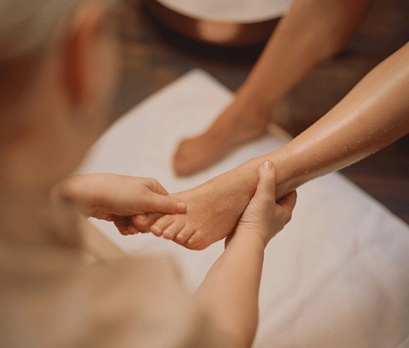 Foot massage therapy on a white towel.