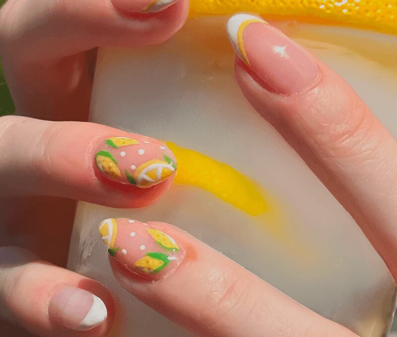 Lemon-themed nail art holding iced drink.